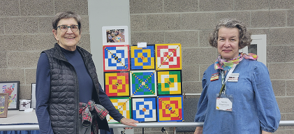 Two seniors displaying colorful crafts
