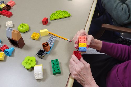 Senior's hand engaging with DUPLO® bricks and connecting them
