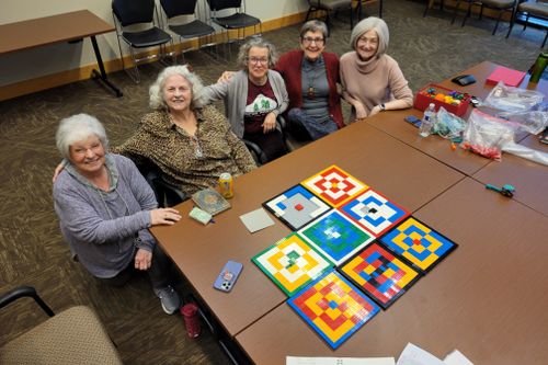 Seniors smiling as they work together with bricks