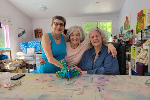 Three seniors posing with each other and their creation