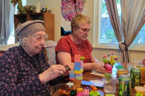 Two people creating with DUPLO® bricks in dining room table