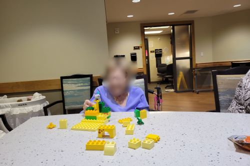 Blurred senior engaging with yellow and green DUPLO® bricks