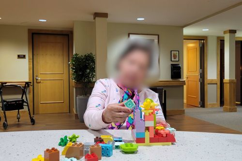 Blurred senior stacking DUPLO® bricks on top of one another