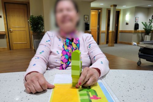 Blurred senior smiling and showing their DUPLO® cactus